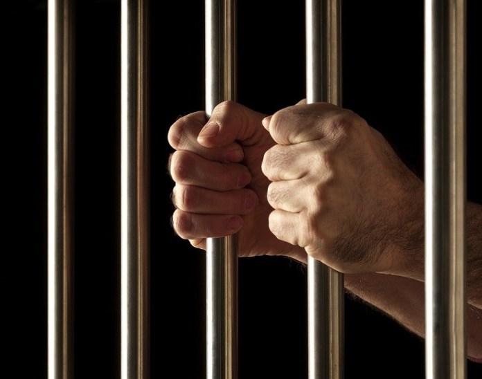 Hands holding prison bars